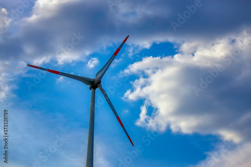 wind turbine against a blue cloudy sky © ptyszku
