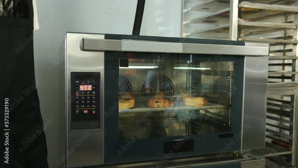 Male hand setting cooking mode or temperature on oven. Finger press button when select function. Arm push modern pushpin. Strudel on metal baking tray in cooker. Male hand setting cooking mode or temperature on oven. Finger press button when select function. Arm push modern pushpin. Strudel on metal baking tray in cooker.