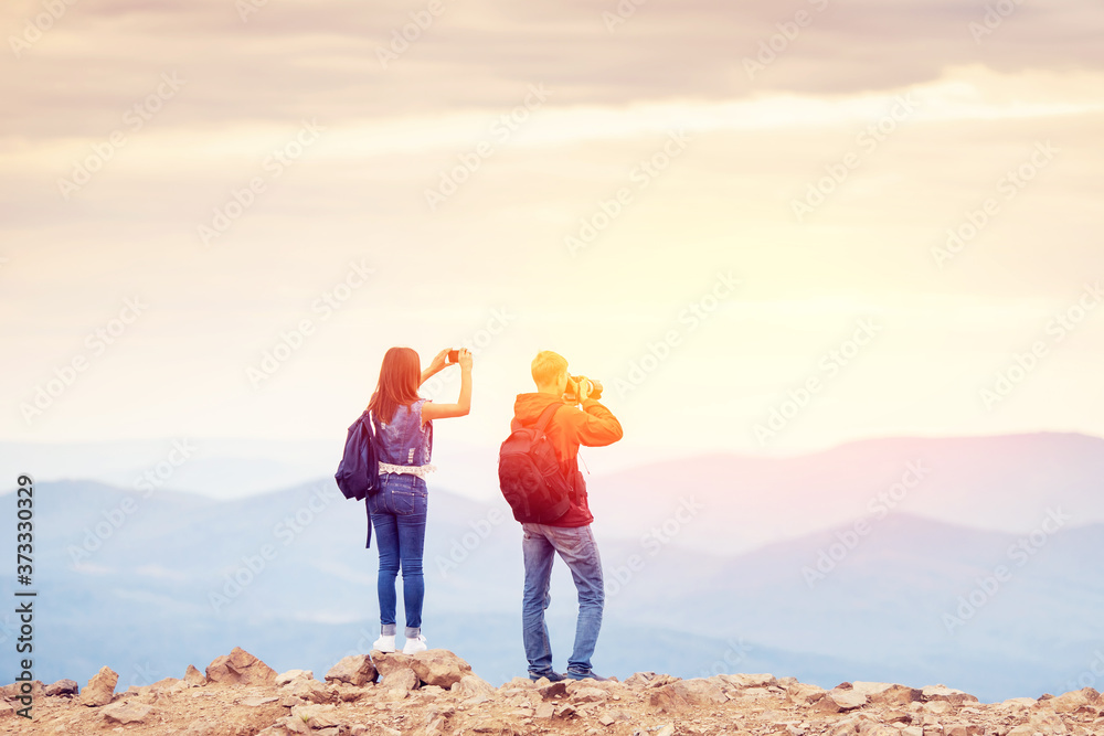 Φωτογραφία Happy travelers man and girl conquered top of mountain, raises hands up with cam