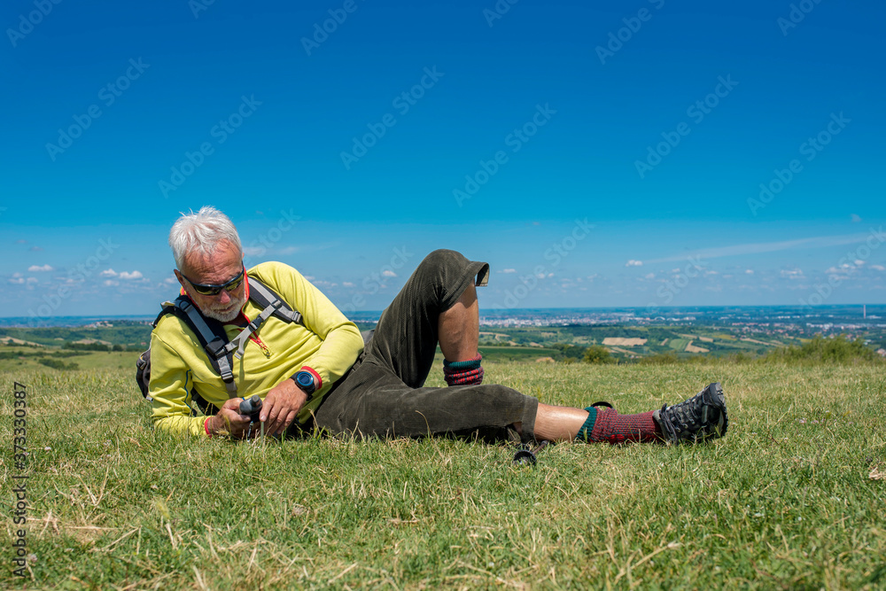 Active senior man, hiker, taking a break in the nature while checking coordinates with hand held GPS navigator device Active senior man, hiker, taking a break in the nature while checking coordinates with hand held GPS navigator device