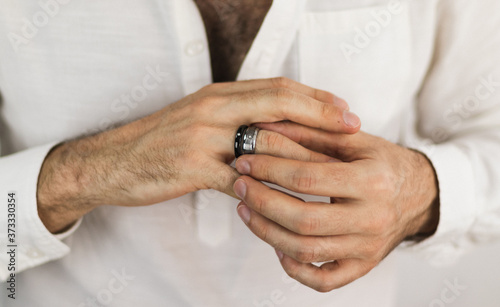 White man's hands putting on two rings with precious stones. Jewelry for men. Engagement ring.