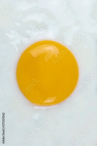 Fried egg sunny side up close up. Vertical top view.