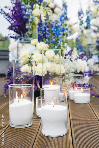 Close-up of white candles on wedding reception with white  blu and violet flower  outdoors. Elegant luxury wedding decoration composition on ceremony place