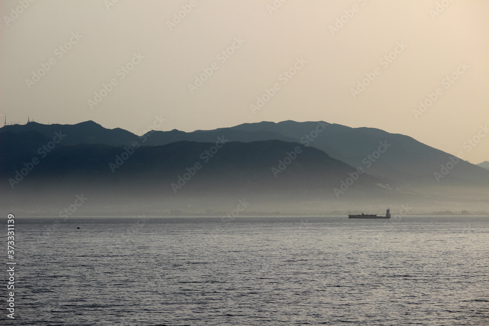 Boat in the sea with fog and mountains in the background