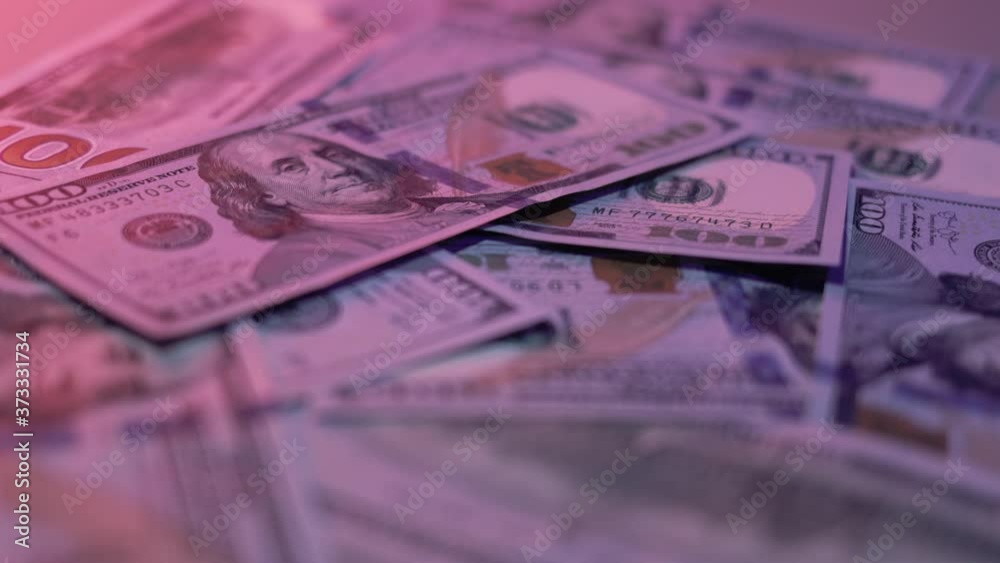 Heap of hundred dollars, throwing banknotes on the table. Close up of heap of money on the table, pink background with heap of one hundred dollars money Heap of hundred dollars, throwing banknotes on the table. Close up of heap of money on the table, pink background with heap of one hundred dollars money