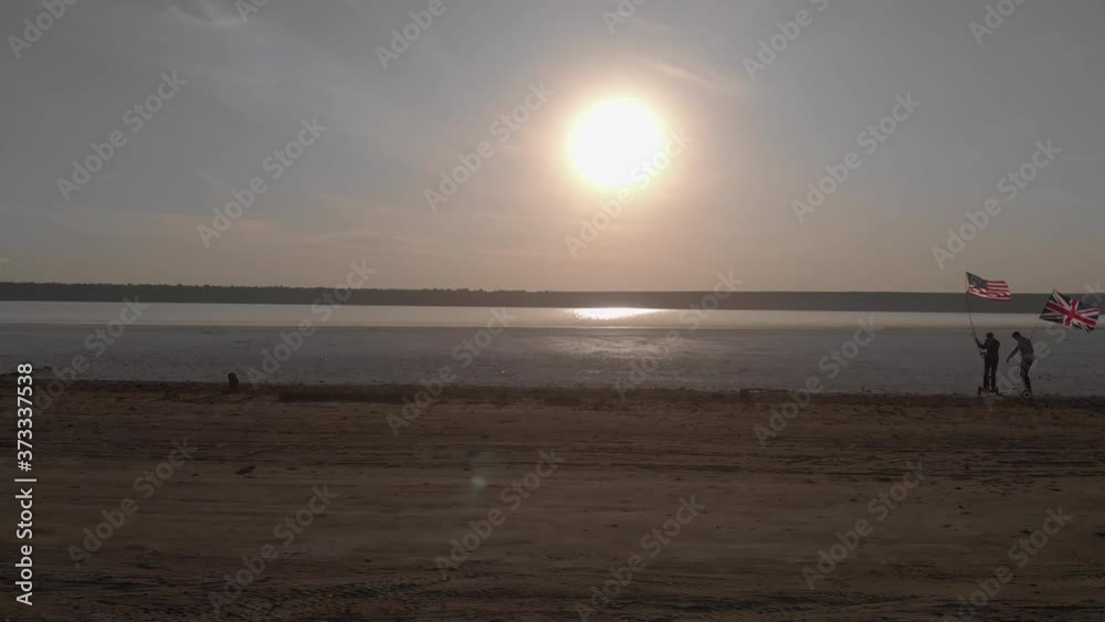 Two businessmen with flags of the United States and Great Britain collided on gyroboards in the middle of the dry lake`s wide shore. Two businessmen with flags of the United States and Great Britain collided on gyroboards in the middle of the dry lake`s wide shore.