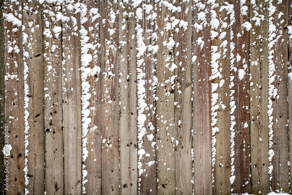 Fototapeta premium The first sticky snowfall of the year adhering to a fence creating interesting white textures on the brown fence boards.