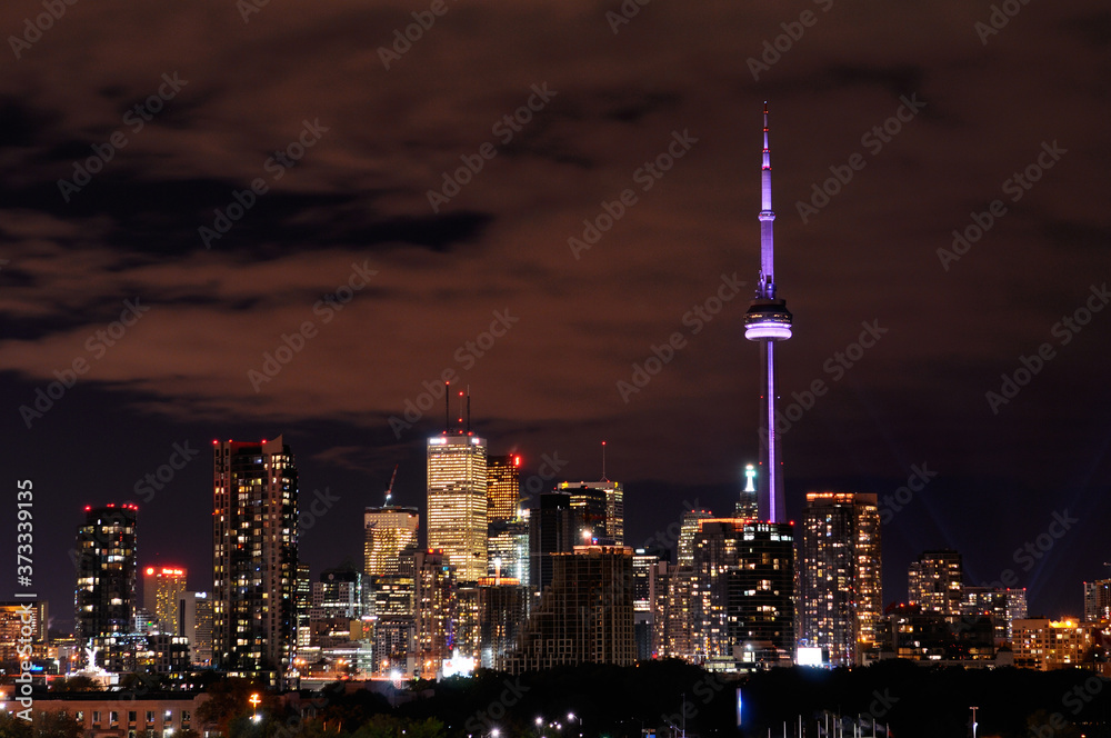 Cityscape of Toronto at night with colored CN Tower and highrise tower lights
