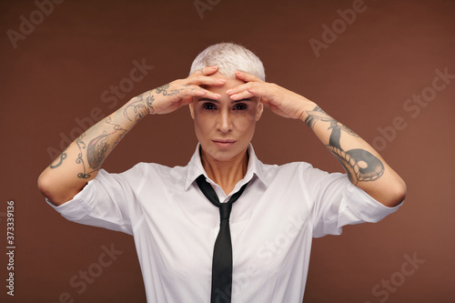 Young blond female with tattoos all over her arms keeping hands on forehead © pressmaster