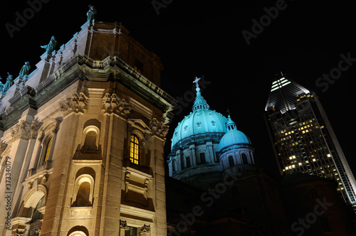 Highrise with Green dome and facade of Mary Queen of the World Basilica Montreal at night photo