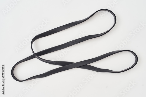 Exercising with elastic expander. Black resistance band for fitness isolated on grey background. Sports equipment