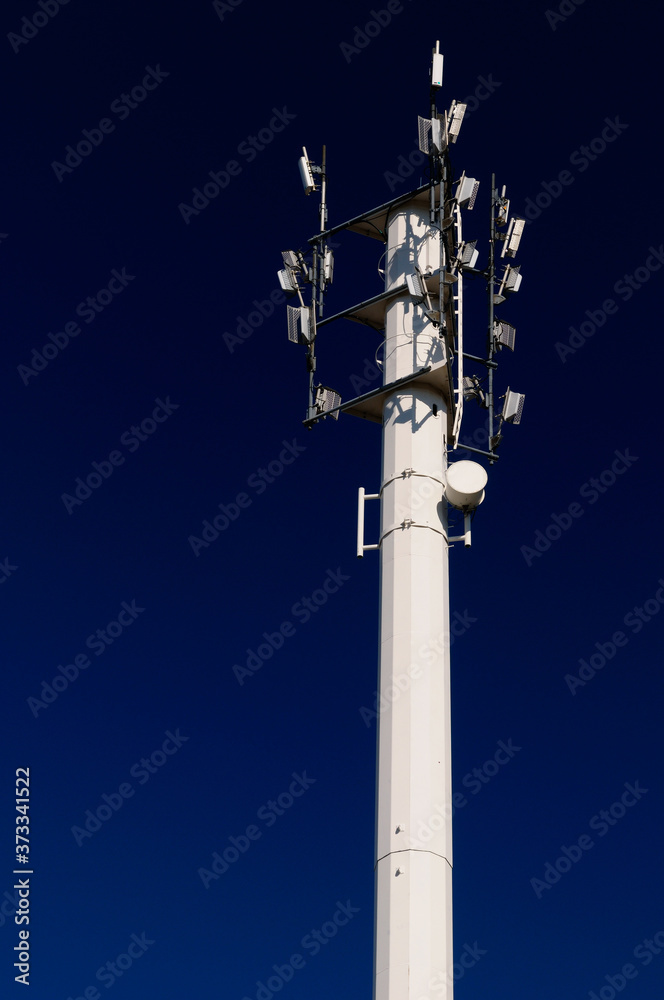 White steel cell phone communications tower against a blue sky close up