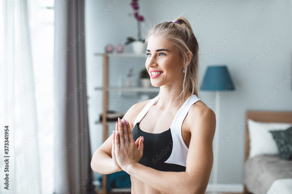 Slim girl practicing yoga at home, wellness, prayer pose.