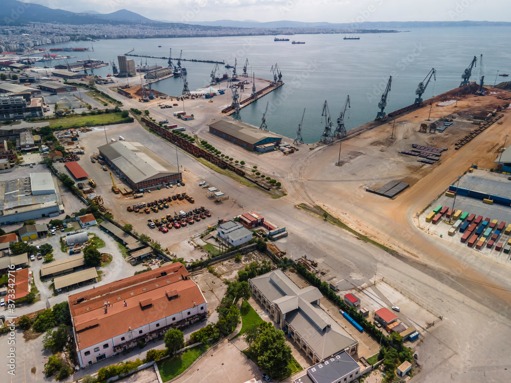 Thessaloniki, Greece aerial drone landscape view of city port area. Day top panorama of large motorized cranes on sea port, with cargo containers on commercial berthing dock pier.