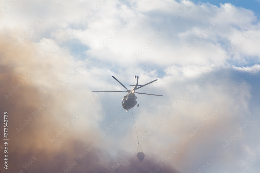 Fire-fighting helicopter against the background of smoke and sky Fire-fighting helicopter against the background of smoke and sky