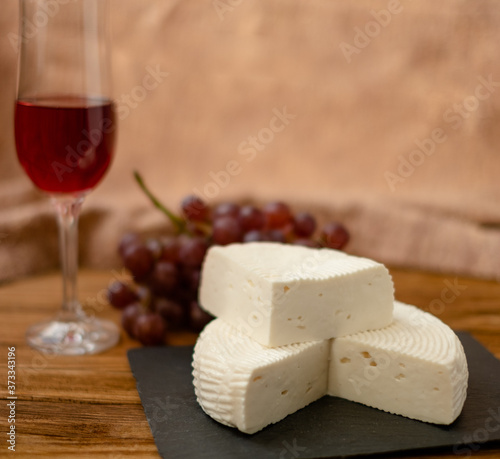 Goat cheese, grapes and wine lie on a wooden table. Cheese at home.