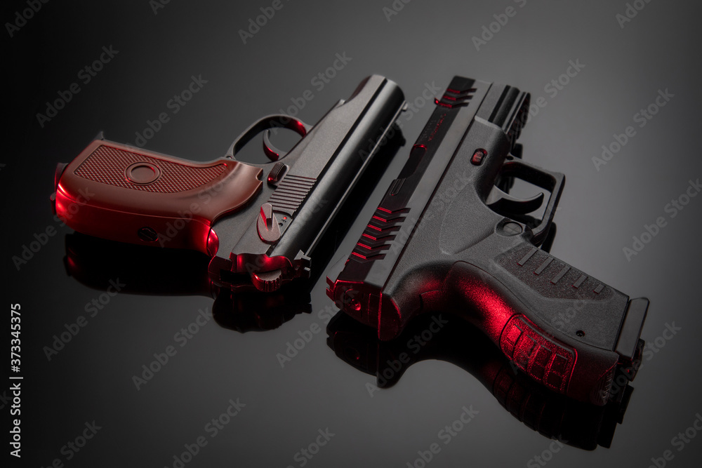 
Two pistols with red illumination on a black gradient background