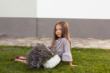 Adorable child in grey dress holding armful of lavender in white basket