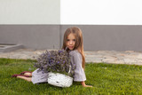Adorable child in grey dress holding armful of lavender in white basket