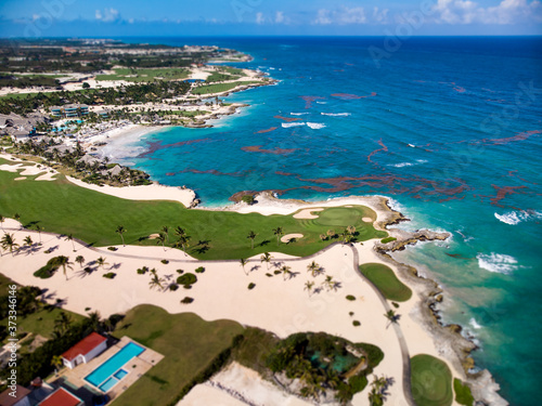 Obraz na płótnie Aerial drone view of golf course at the rocky shore of Caribbean Sea with spots
