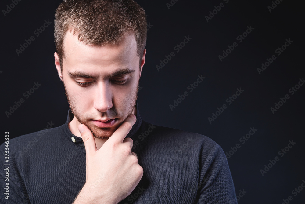 Portrait of an emotional handsome young man, on a black background in the studio, who stands in a brooding pose. Expression of emotions and feelings Portrait of an emotional handsome young man, on a black background in the studio, who stands in a brooding pose. Expression of emotions and feelings