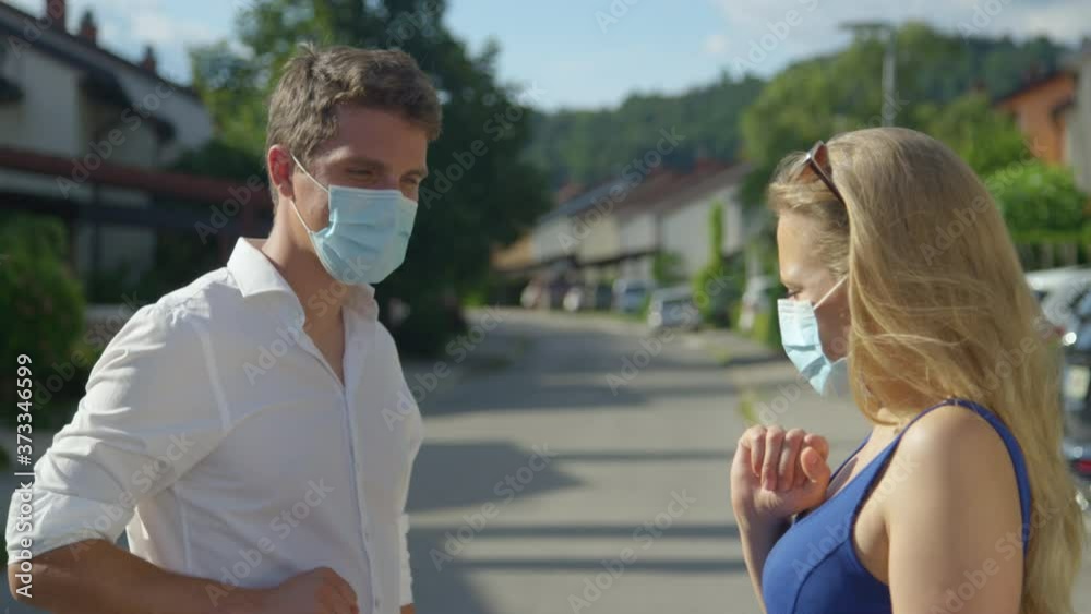SLOW MOTION, CLOSE UP, PORTRAIT: Responsible man and woman greet by touching elbows instead of shaking hands as they meet in the middle of the street running through the idyllic tranquil suburbs. SLOW MOTION, CLOSE UP, PORTRAIT: Responsible man and woman greet by touching elbows instead of shaking hands as they meet in the middle of the street running through the idyllic tranquil suburbs.