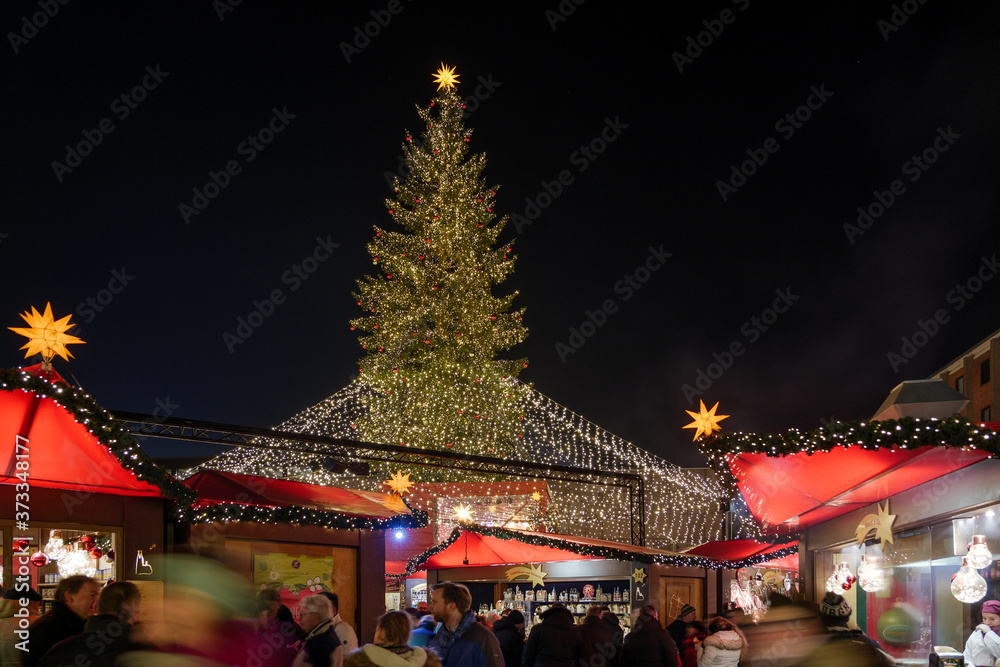 Night atmosphere of Weihnachtsmarkt, Christmas Market, with various decorated illuminate stalls surround  big Christmas tree at plaza in front of Cologne Cathedral in Köln, Germany.