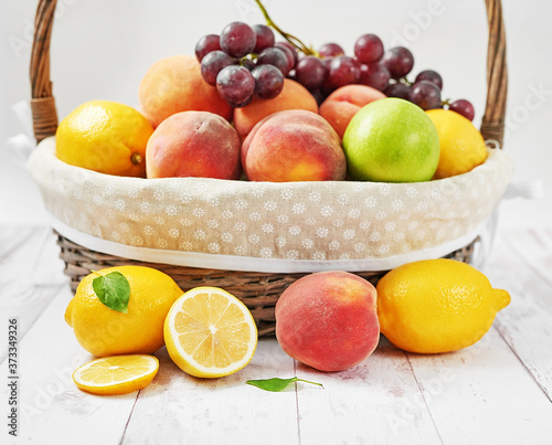 Basket of frkuts apples  peaches  lemons  grapes. Summer postcard. Hello summer  Harvesting. Healthy food and nutrition. Fruit background. Healthy cozy breakfast. Natural organic products. Vitamins