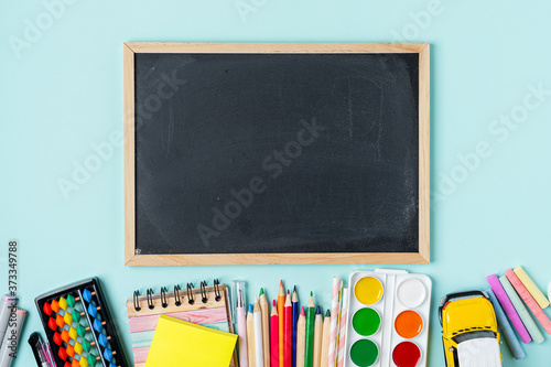 Concept Back To School Color Chalk Pencil Notebook Stationery on blue Blackboard Background. Design Copy Space and mock up Supplies Top View Flat Lay