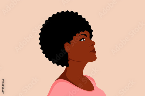 Beautiful black woman. Young african american woman keep her head up. Beautiful face and hairstyle. Side view. Isolated on a beige background.