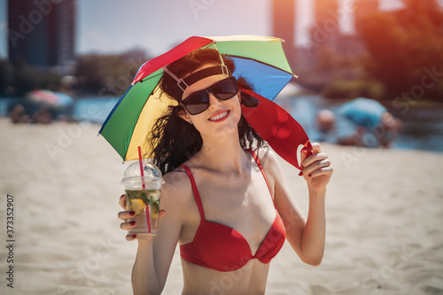 young female sitting on urban beach in medical mask and drinkg mojito cocktail photo