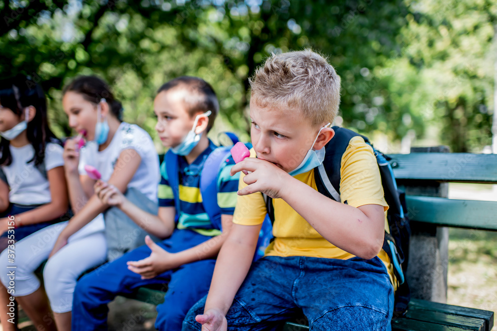 Group of children eating ice cream outside. They are wearing a protective face mask down. Group of children eating ice cream outside. They are wearing a protective face mask down.