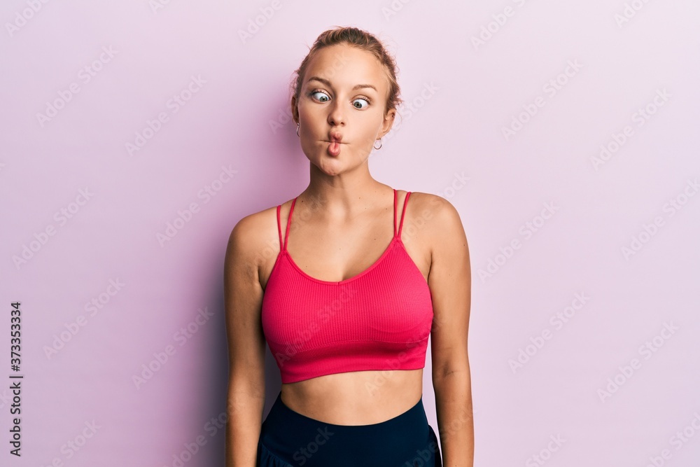 Beautiful caucasian woman wearing sportswear making fish face with lips, crazy and comical gesture. funny expression. Beautiful caucasian woman wearing sportswear making fish face with lips, crazy and comical gesture. funny expression.