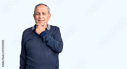 Senior handsome man wearing casual polo looking confident at the camera smiling with crossed arms and hand raised on chin. thinking positive.