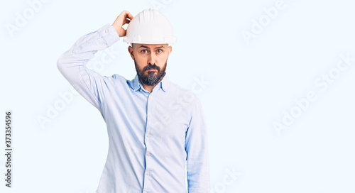 Quadro su tela Young handsome man wearing architect hardhat confuse and wonder about question
