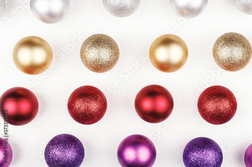 Pattern of different brightly colored Christmas spheres on white background. From top view. Christmas decorations. Christmas wallpaper.