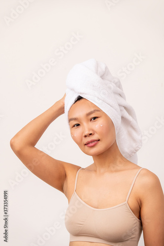 Young pretty female of Asian ethnicity with towel on head and beige tanktop