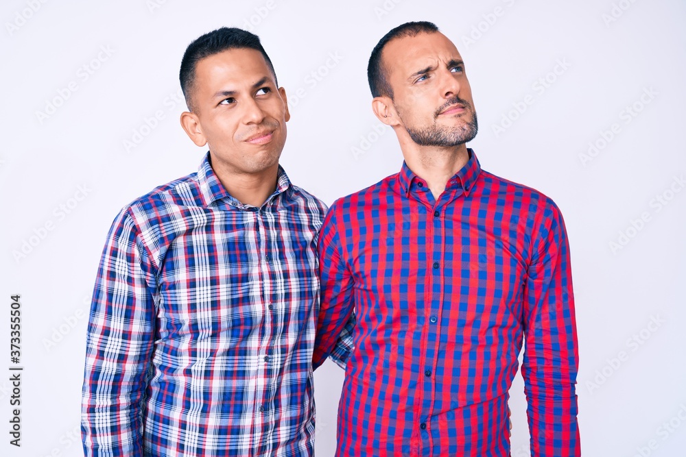 Young gay couple of two men wearing casual clothes smiling looking to the side and staring away thinking. Young gay couple of two men wearing casual clothes smiling looking to the side and staring away thinking.
