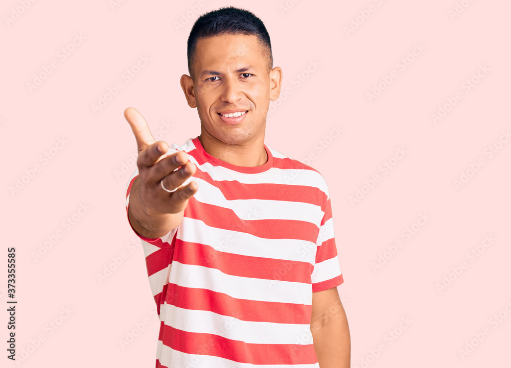 Young handsome latin man wearing casual clothes smiling friendly offering handshake as greeting and welcoming. successful business. Young handsome latin man wearing casual clothes smiling friendly offering handshake as greeting and welcoming. successful business.