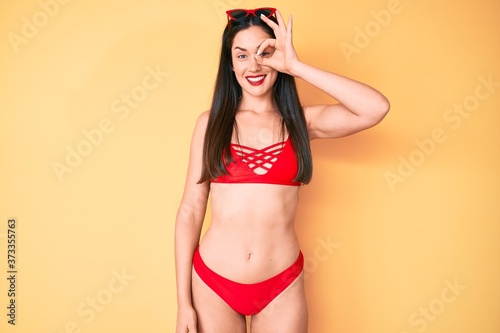 Young beautiful caucasian woman wearing bikini smiling happy doing ok sign with hand on eye looking through fingers