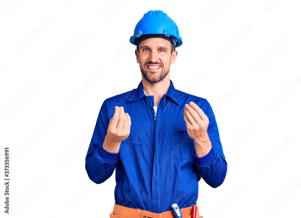 Young handsome man wearing worker uniform and hardhat doing money gesture with hands, asking for salary payment, millionaire business Young handsome man wearing worker uniform and hardhat doing money gesture with hands, asking for salary payment, millionaire business