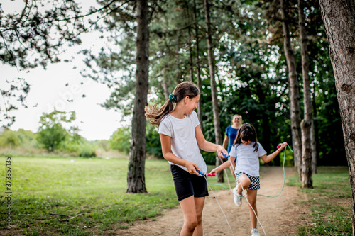 School children in white t shirts skipping ropes at public park