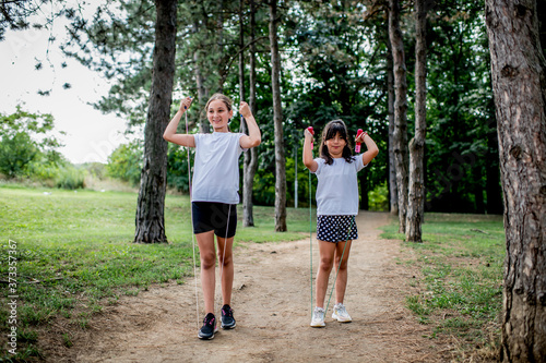 Fototapeta Naklejka Na Ścianę i Meble -  School children in white t shirts skipping ropes at public park