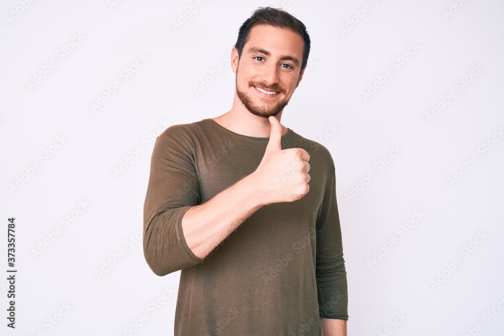 Young handsome man wearing casual clothes doing happy thumbs up gesture with hand. approving expression looking at the camera showing success. Young handsome man wearing casual clothes doing happy thumbs up gesture with hand. approving expression looking at the camera showing success.