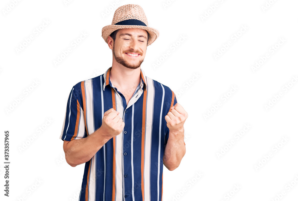 Young handsome caucasian man wearing summer hat excited for success with arms raised and eyes closed celebrating victory smiling. winner concept. Young handsome caucasian man wearing summer hat excited for success with arms raised and eyes closed celebrating victory smiling. winner concept.