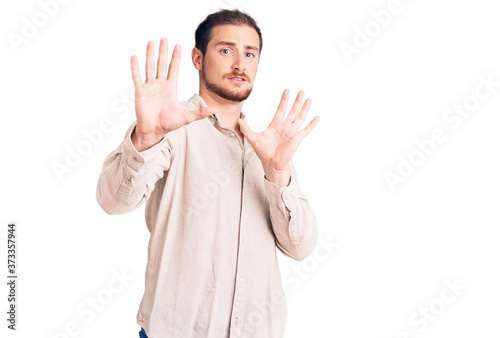 Young handsome caucasian man wearing casual clothes afraid and terrified with fear expression stop gesture with hands, shouting in shock. panic concept.