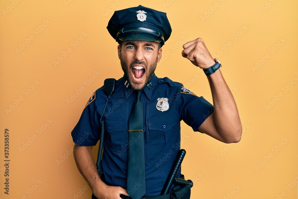 Handsome hispanic man wearing police uniform angry and mad raising fist frustrated and furious while shouting with anger. rage and aggressive concept. Handsome hispanic man wearing police uniform angry and mad raising fist frustrated and furious while shouting with anger. rage and aggressive concept.