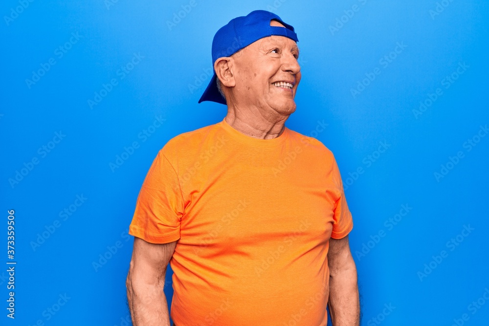 Senior handsome grey-haired man wearing casual t-shirt and cap over blue background looking to side, relax profile pose with natural face and confident smile. Senior handsome grey-haired man wearing casual t-shirt and cap over blue background looking to side, relax profile pose with natural face and confident smile.