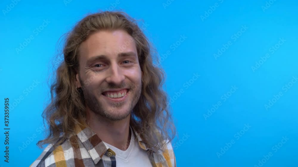 The long-haired male rock musician smiles and nods in agreement. The long-haired male rock musician smiles and nods in agreement.