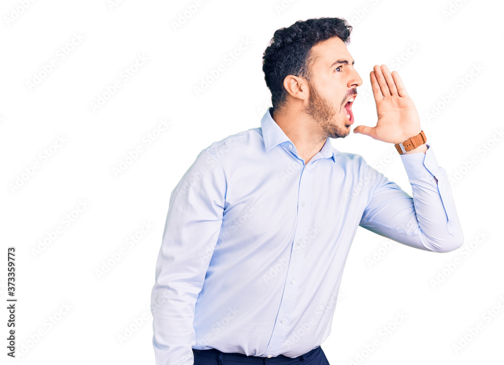 Young hispanic man wearing business clothes shouting and screaming loud to side with hand on mouth. communication concept. Young hispanic man wearing business clothes shouting and screaming loud to side with hand on mouth. communication concept.
